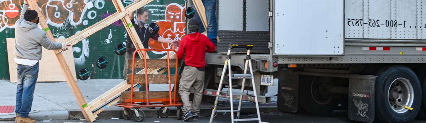frete de retorno: vários ajudantes ajudam a carregar vidro em um caminhão