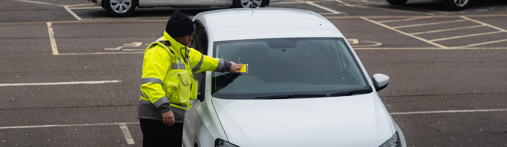 Controle de multas: um fiscal afixa um multa no parabrisas de um carro